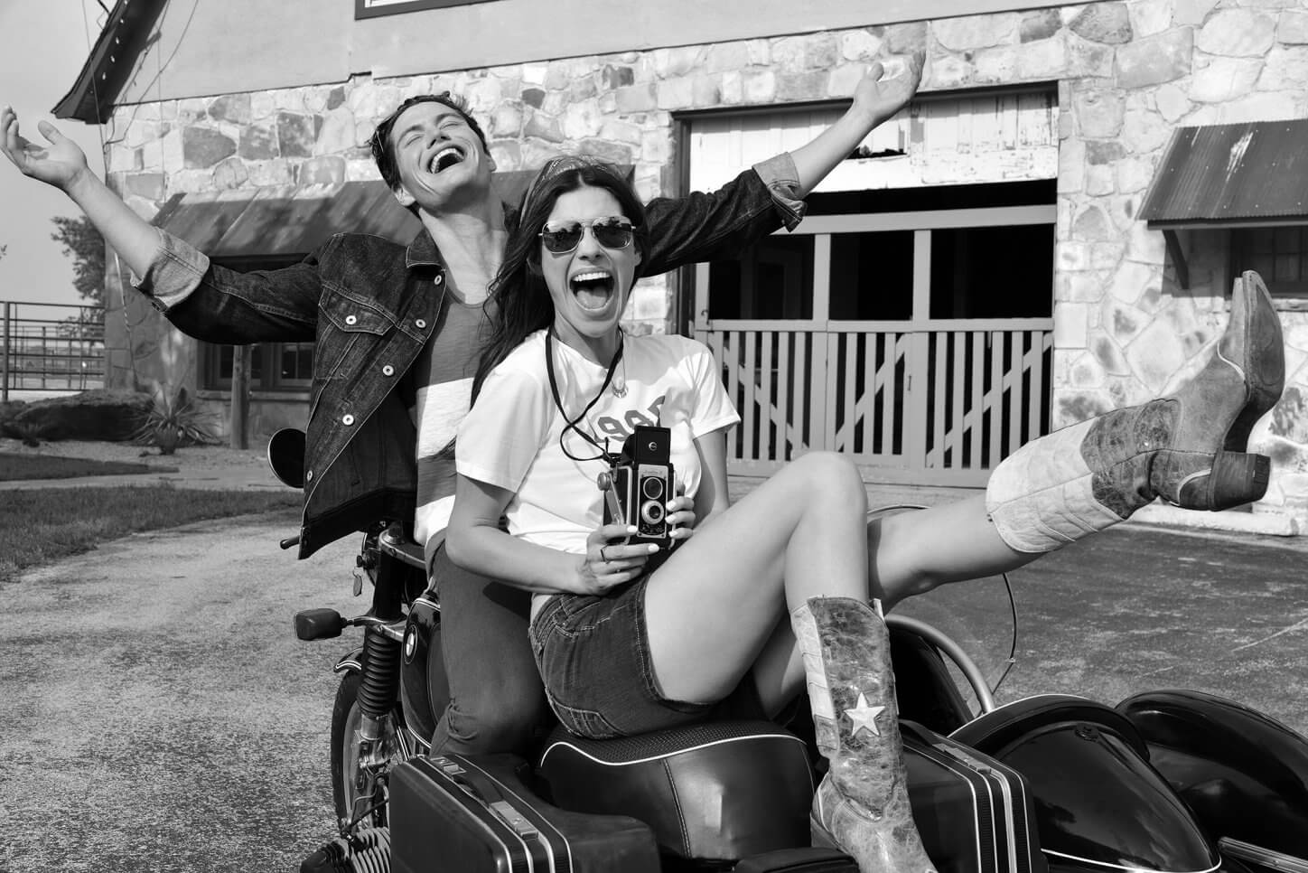 beautiful young couple with vintage camera laughing in black and white