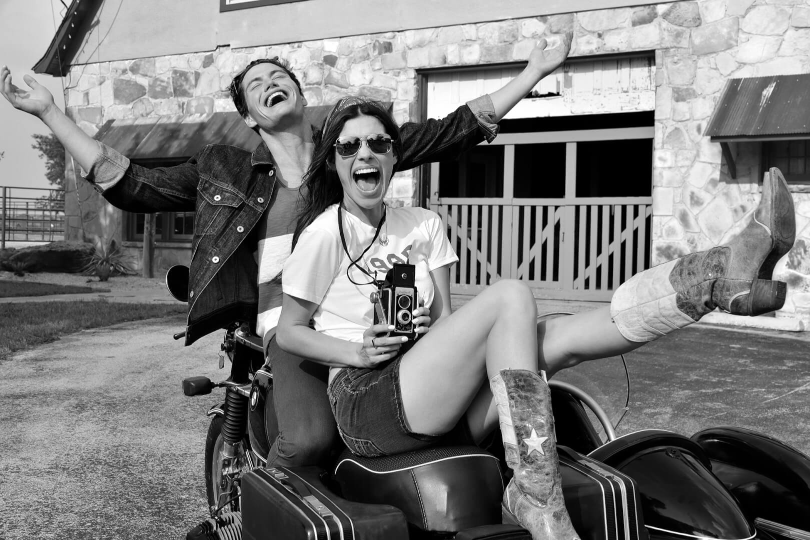 beautiful young couple with vintage camera laughing in black and white